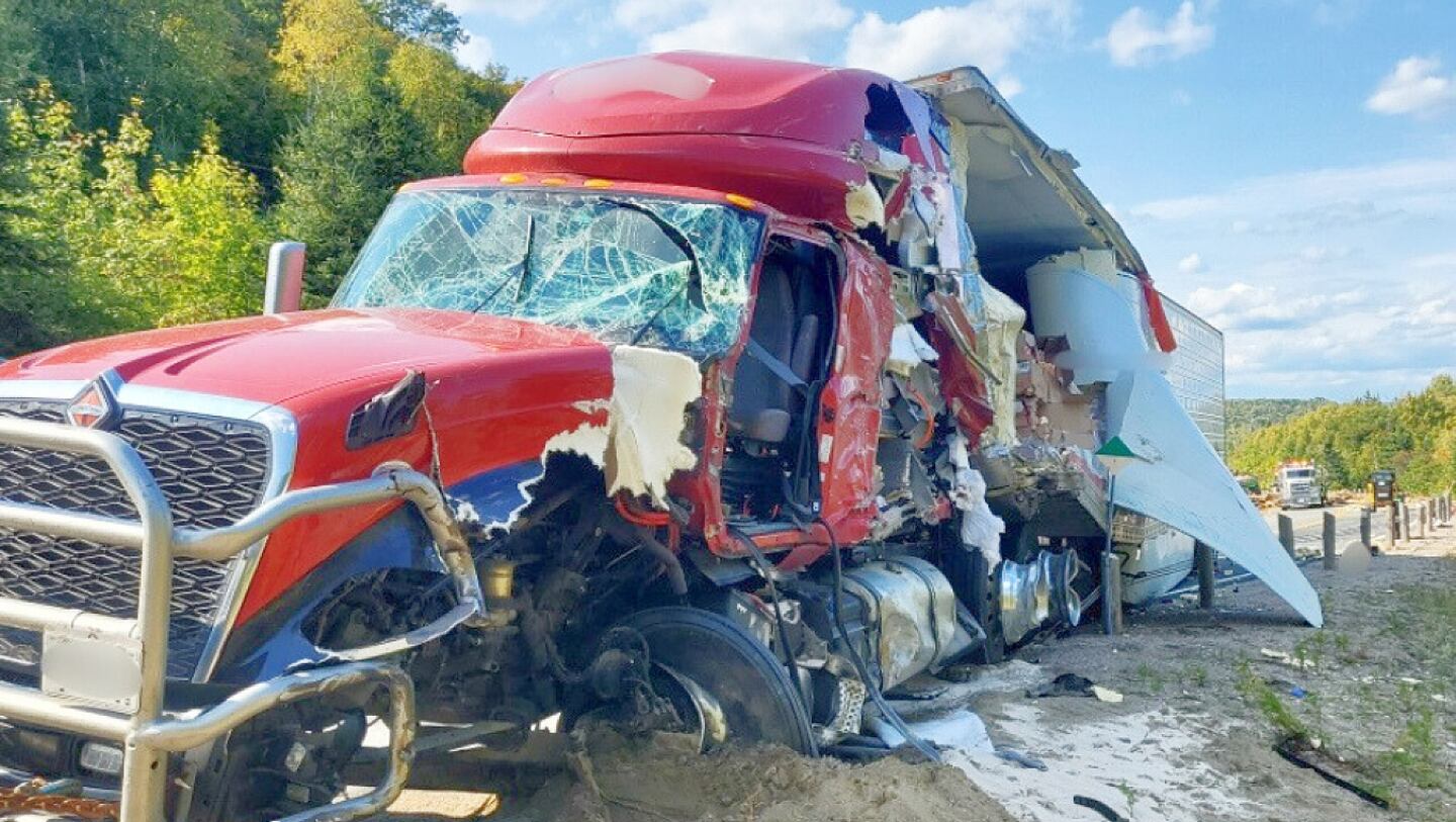 Destroyed red transport truck after a highway collision, representing the rising safety dangers tied to the Driver Inc Canada crisis.