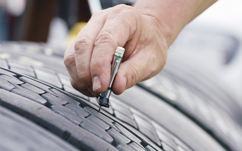 Measuring tire tread depth during a Schedule 1 tire inspection for Ontario commercial vehicles.